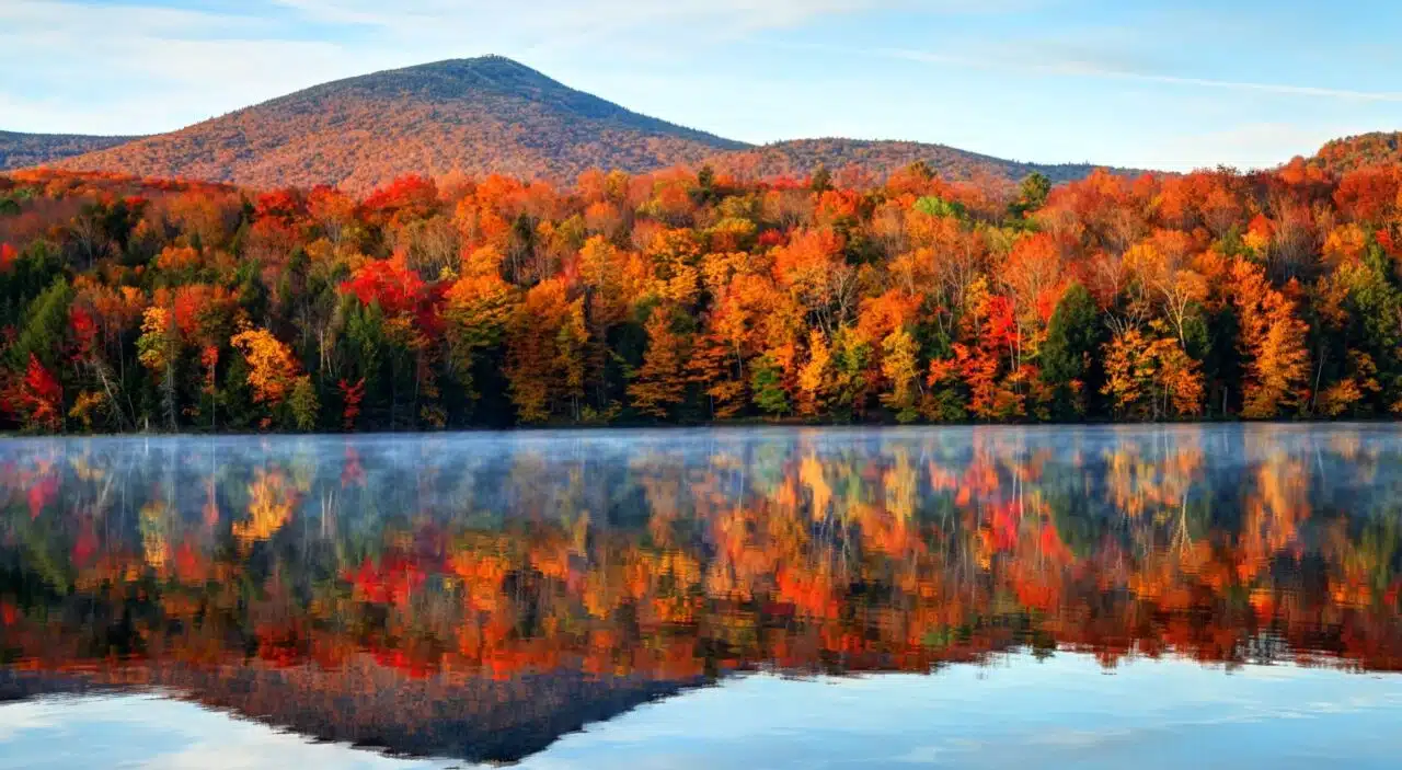 tranquil lake surrounded by autumn trees in vermont